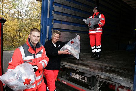 v.l. Rotkreuzler Sebastian Kulle, Evelyn Trapp und Christina Hinkel des DRK-Ortsvereins Siegen-Nord beim Entladen der Kleiderspenden auf einen bereitgestellten LKW unter der HTS in Geisweid.